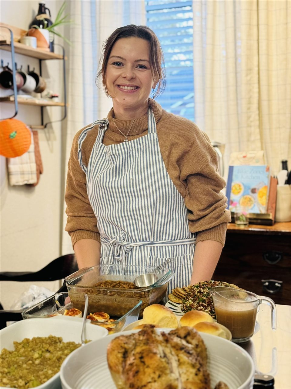 Candice smiling in her kitchen behind a table of home-cooked food.